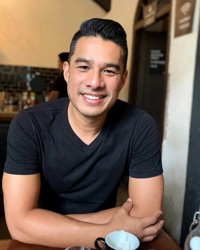 John, who designs and builds every Dactyl website, sitting at a cafe table with his arms crossed